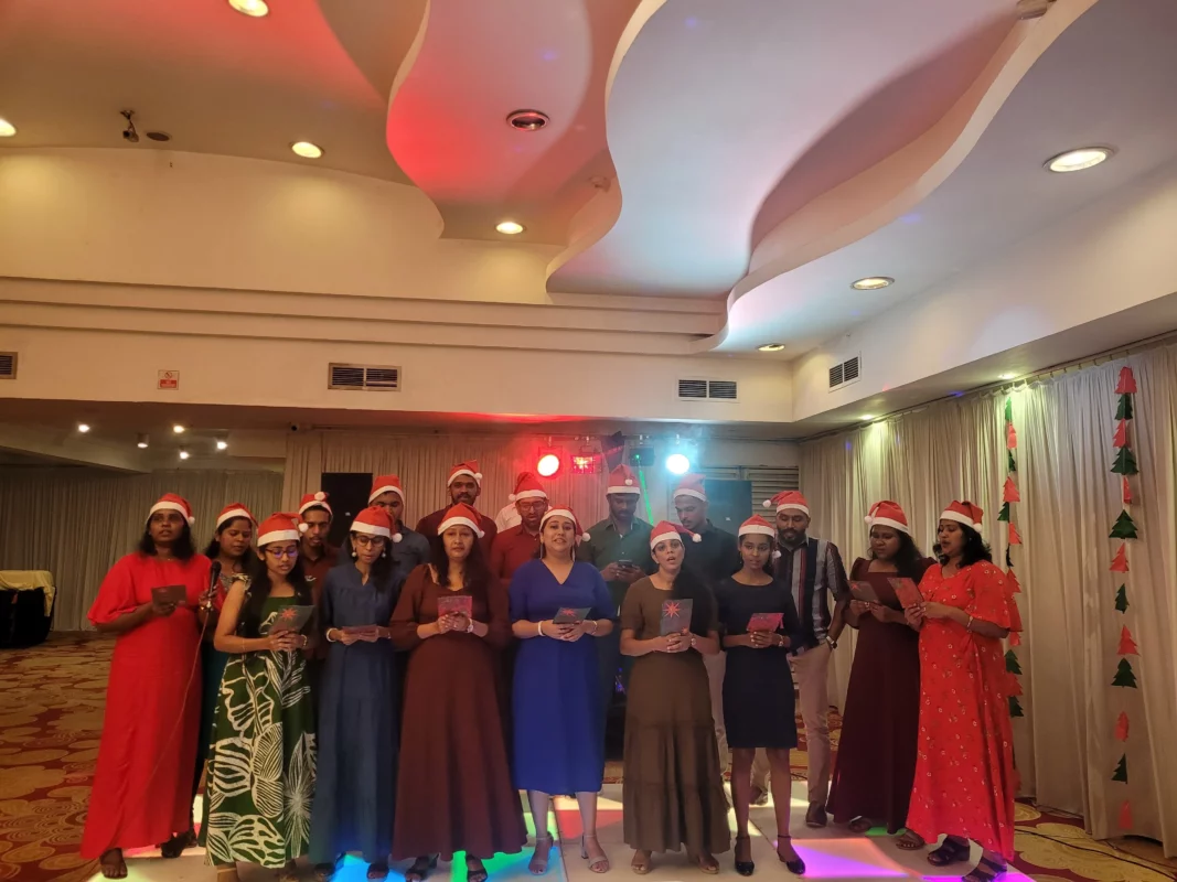 A group of employees conducting a carol with Santa Clause Hats