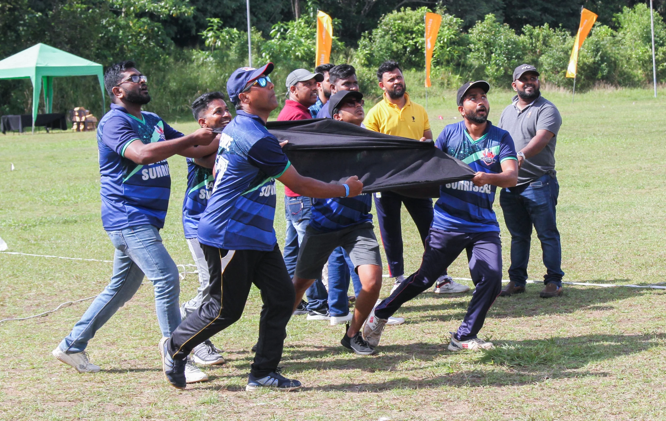 Few employees trying to catch using a black cloth as a team builing activity