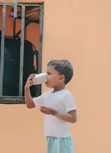 A child drinking water from a stainless steel cup